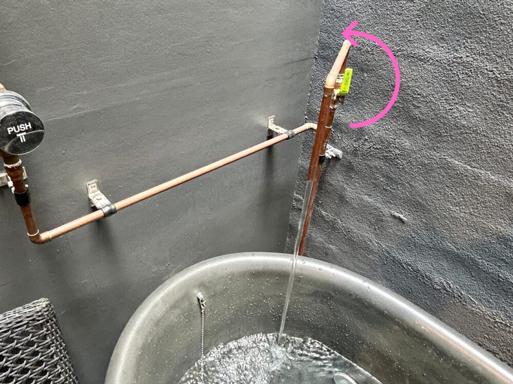 Green-handled water supply valve near the cold plunge bathtub